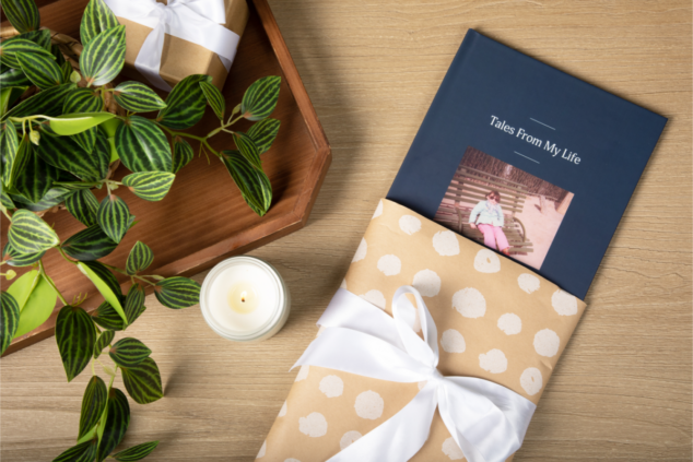 Remento gift book in a pretty package on a table with flowers and a candle